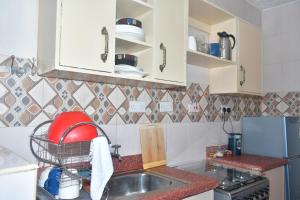 una cucina con armadi bianchi e lavandino di Homestyle Haven with Secure Parking & Free WiFi a Embu