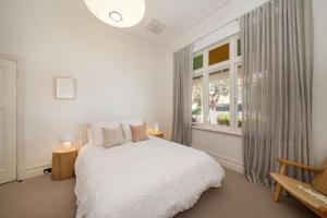 um quarto branco com uma cama e uma janela em Timeless Gem in Malvern East em Carnegie