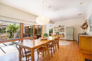 a kitchen and dining room with a wooden table and chairs at Bessie at Merricks Beach in Coles Beach +21 photos