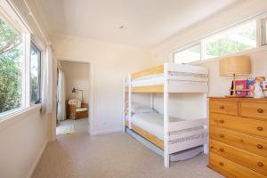 a bedroom with two bunk beds and a dresser at Bessie at Merricks Beach in Coles Beach