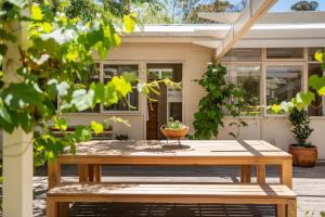 a wooden picnic table in front of a house at Bessie at Merricks Beach in Coles Beach