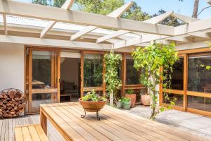 a patio with a wooden deck with a pergola at Bessie at Merricks Beach in Coles Beach