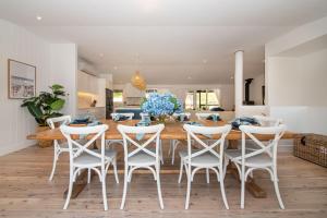 a dining room with a wooden table and white chairs at Dundas on the Beach at St Andrews in Saint Andrews Beach