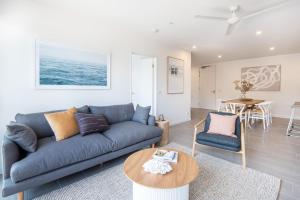 ein Wohnzimmer mit einer blauen Couch und einem Tisch in der Unterkunft Beachfront Apartment with lots of Wow in Rosebud