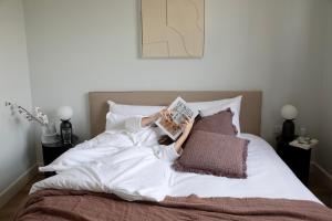 a woman laying in bed reading a book at Gulaid House Knightsbridge by Bob W London in London