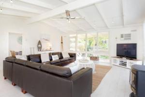a living room with a brown couch and a tv at Dromanas Beachside Hideaway in Dromana