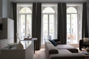 Gulaid House Knightsbridge by Bob W London في لندن: غرفة معيشة مع نوافذ كبيرة وأريكة