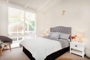 a white bedroom with a bed and a window at Dromanas Beachside Hideaway in Dromana