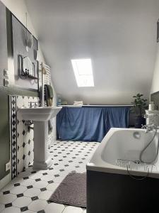 La salle de bains est pourvue d'une baignoire blanche et d'un lavabo. dans l'établissement Tour St Sauveur, à Bellême