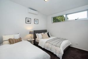 two beds in a white room with a window at Elwood Village Entertainer in Melbourne