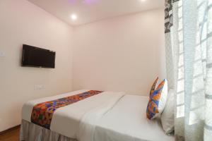 a bedroom with a bed and a flat screen tv at FabExpress Shivas Inn in Nagpur