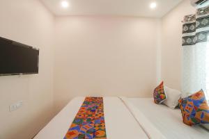 um quarto com uma cama e uma televisão na parede em FabExpress Shivas Inn em Nagpur