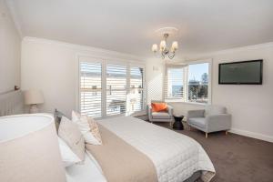 a bedroom with a bed and a chair and a tv at Sandy Village Retreat Heated Pool Bay Views in Sandringham