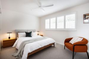 a white bedroom with a bed and a chair at The Pavilion with pool St Andrews Beach in Saint Andrews Beach +32 photos