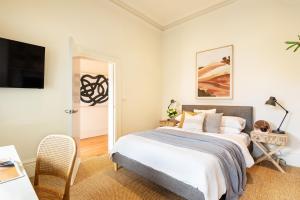 a white bedroom with a bed and a tv at Grand Victoria Beach House in Melbourne