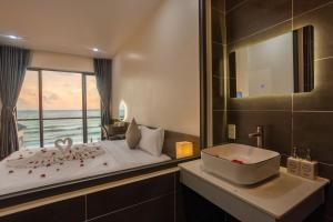 ein Schlafzimmer mit einer Badewanne, einem Waschbecken und einem Fenster in der Unterkunft Wave Sound Beach House Phu Quoc in Phu Quoc
