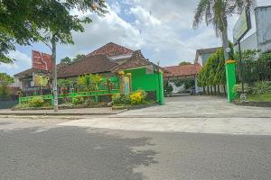 een groen gebouw met bloemen voor een straat bij Collection O 90589 Palem Garden Hotel in Tulungagung