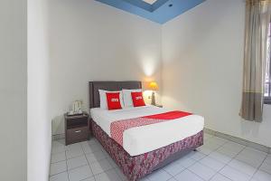 een slaapkamer met een bed met rode kussens bij Collection O 90589 Palem Garden Hotel in Tulungagung