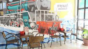 a dining room with a mural of a train on the wall at 107 Hostel (One-O-Seven Hostel) in Kanchanaburi City