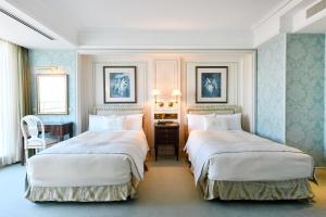 two beds in a room with blue walls at Hotel New Grand in Yokohama