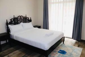 Schlafzimmer mit einem großen weißen Bett und einem großen Fenster in der Unterkunft Yohana Residences in Nairobi