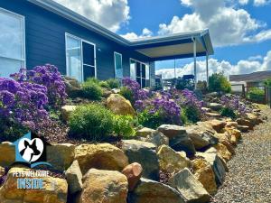 a yard with rocks and purple flowers in front of a house at Brand New 3 Bed 2 Bath with Sea Views in Encounter Bay