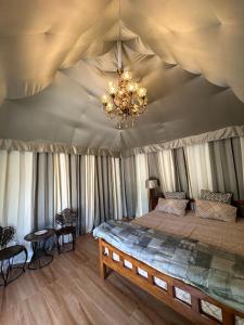 a bedroom with a bed in a tent with a chandelier at Chitragarh Farm in New Delhi
