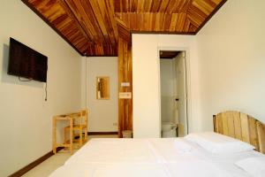 a bedroom with a white bed and a television at Pallet Homes - Ledesco in Iloilo City