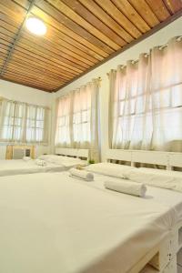 three beds in a room with white curtains at Pallet Homes - Ledesco in Iloilo City