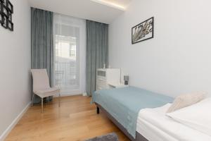 a bedroom with a bed and a desk and a window at Spacious Lodygowa Apartment Ideal for Families by Renters in Warsaw