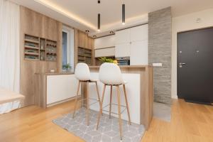 a kitchen with two white stools at a counter at Spacious Lodygowa Apartment Ideal for Families by Renters in Warsaw