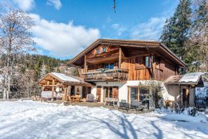 uma cabana de madeira na neve com um quintal em chalet les ecureuils em Saint-Jean-de-Sixt