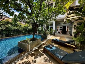 a swimming pool with a tree next to a house at Babel Boutique in Siem Reap