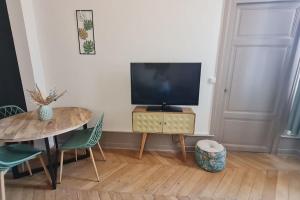 a living room with a table and a television at L'Escapade Bohême in Vienne