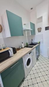 a kitchen with a washing machine and a sink at L'Escapade Bohême in Vienne