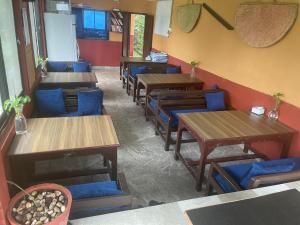 un restaurante con mesas de madera y sillas azules en Himalaya Serene View Guest House & Farm Stay en Deorāli