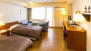 a hotel room with two beds and a desk at Haboro Onsen Sunset Plaza in Haboro