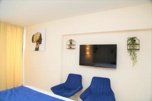 two blue chairs in a room with a flat screen tv at Orbi City Beach Side Apartments in Batumi