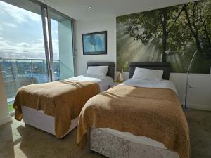 two beds in a room with a large window at Skyline Retreat with Unmatched Panaromic Views and Secure Parking in Liverpool