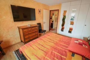 - une chambre avec un lit, une commode et une télévision dans l'établissement Super appartement au coeur de Martigny, à Martigny-Ville