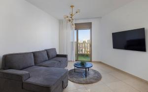 ein Wohnzimmer mit einem Sofa und einem TV in der Unterkunft Mishkenot Ahuma luxury apartment in Jerusalem