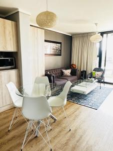ein Wohnzimmer mit einem Glastisch und weißen Stühlen in der Unterkunft WATERS EDGE 103 in Kapstadt