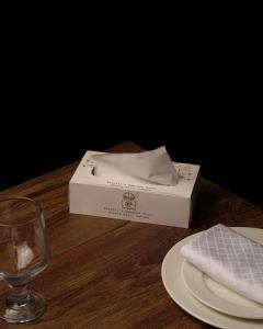 a box on a table with a plate and a glass at Faletti's Express- Shimla Hill in Lahore