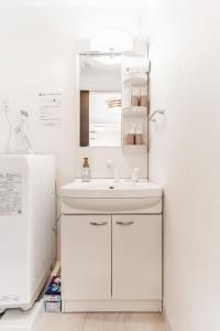 a bathroom with a sink and a mirror next to a refrigerator at 川HOUSE旭 in Osaka