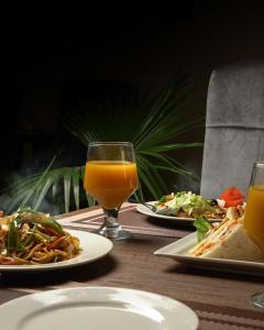 una mesa con platos de comida y un vaso de zumo de naranja en Faletti's Express- Shimla Hill en Lahore