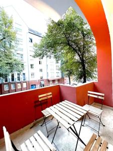 - deux tables et des chaises sur une terrasse dotée d'un mur rouge dans l'établissement Schönes großes Apartment im Zentrum Berlins, à Berlin