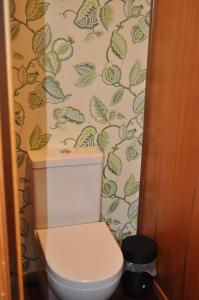 a bathroom with a toilet with a leafy wallpaper at Lakeside Cottage with Jetty at Lake Tarawera in Rotorua +21 photos