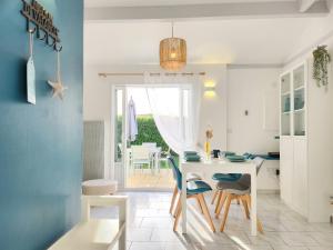 a kitchen and dining room with a white table and chairs at Maison Les Embruns avec piscine collective in La Faute-sur-Mer