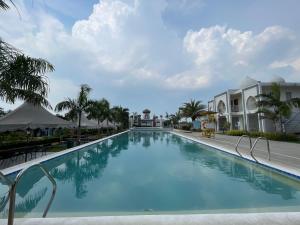 a large swimming pool with palm trees and buildings at Torres Farm Resort powered by Cocotel in Naic