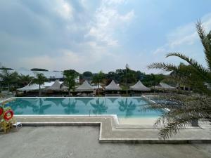 a large swimming pool with umbrellas in a resort at Torres Farm Resort powered by Cocotel in Naic